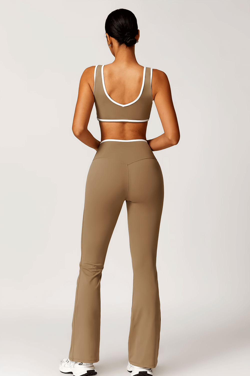 Woman wearing stylish high-waist flared yoga pants in tan, showcasing a chic bell-bottom design with an elastic waist, ideal for activewear.